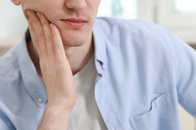 Photo of Man suffering from toothache at home, closeup