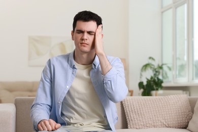 Man suffering from headache on sofa at home