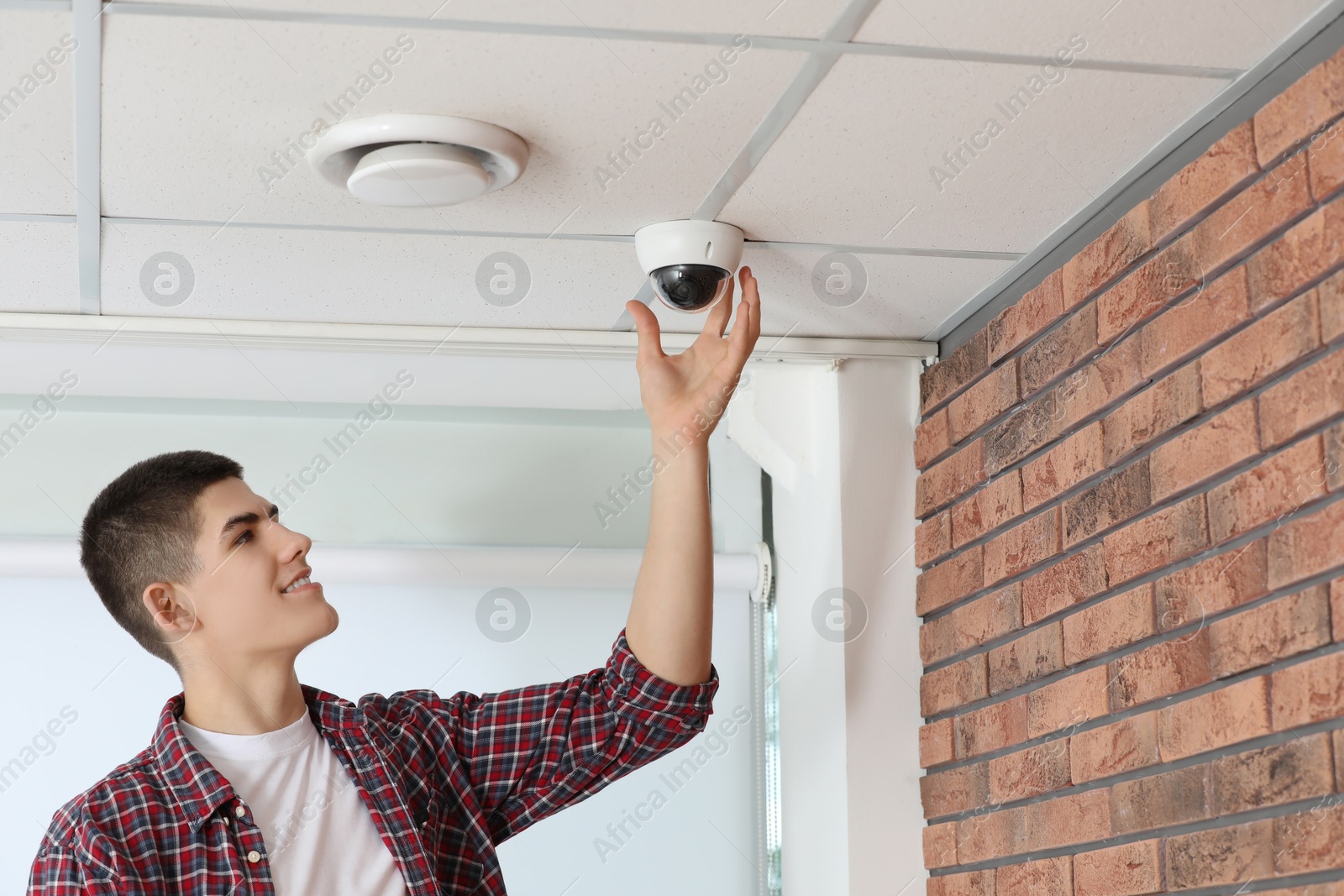 Photo of Technician installing CCTV camera on ceiling indoors