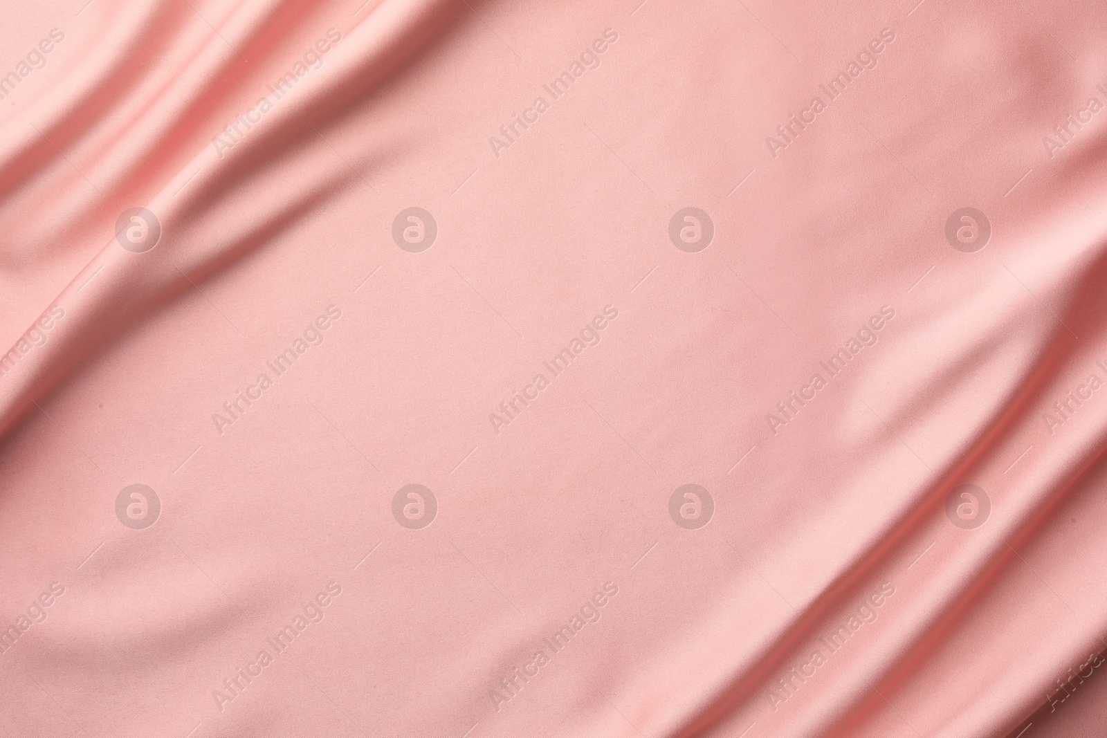 Photo of Crumpled pink silk fabric as background, top view. Space for text