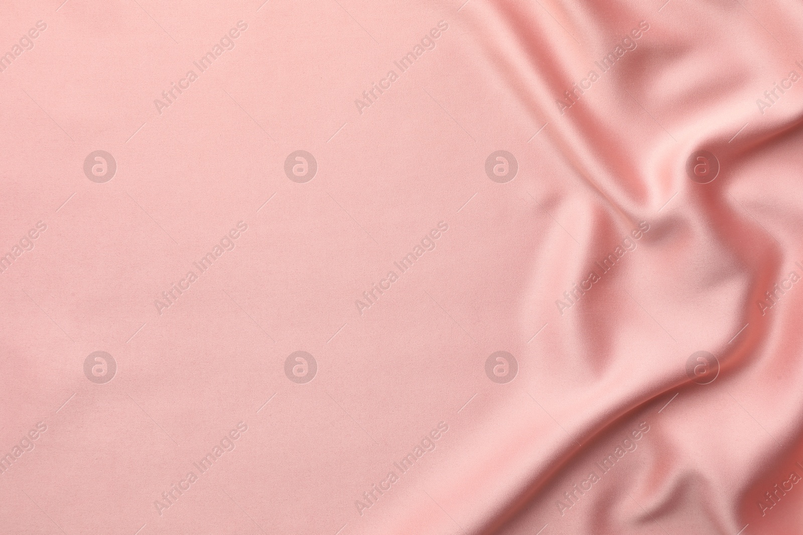 Photo of Crumpled pink silk fabric as background, top view. Space for text