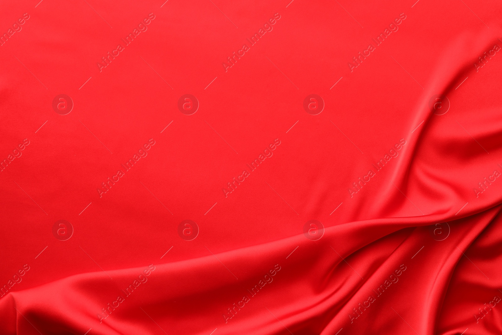 Photo of Crumpled red silk fabric as background, top view. Space for text