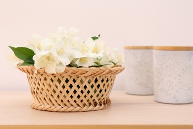 Photo of Beautiful jasmine flowers in wicker basket and containers on wooden table