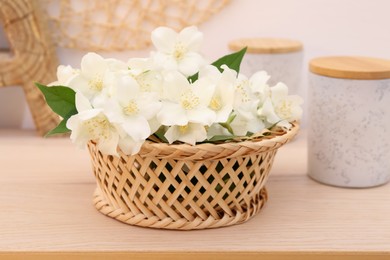 Beautiful jasmine flowers in wicker basket on wooden table