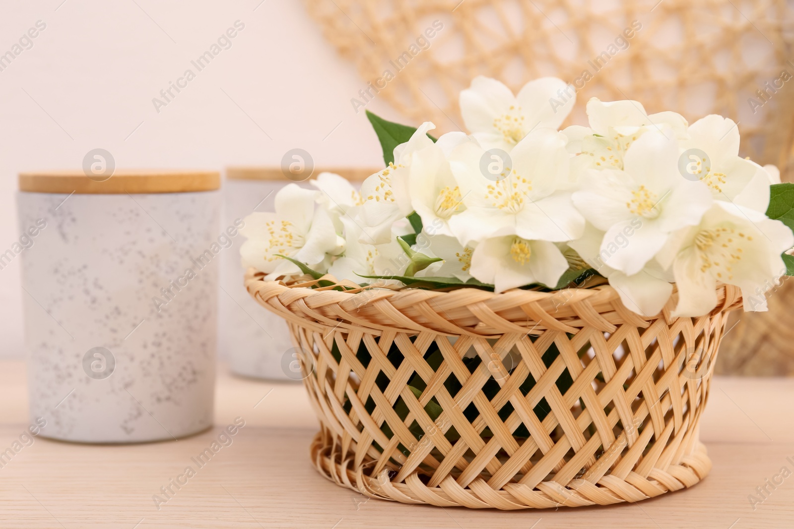 Photo of Beautiful jasmine flowers in wicker basket on wooden table