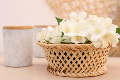 Beautiful jasmine flowers in wicker basket on wooden table