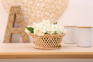 Beautiful jasmine flowers in wicker basket, containers and decor on wooden table