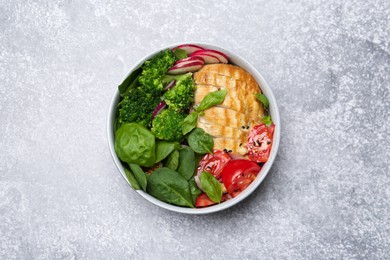 Photo of Healthy meal. Delicious chicken, vegetables and spinach in bowl on light grey table, top view