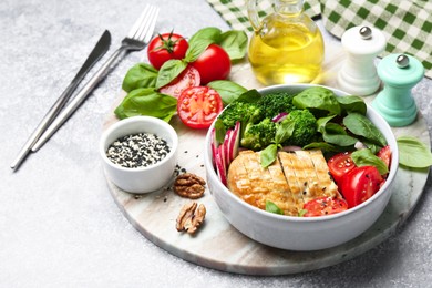 Photo of Healthy meal. Delicious chicken, vegetables and spinach served on light grey table