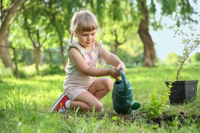 Cute little girl watering tree in garden