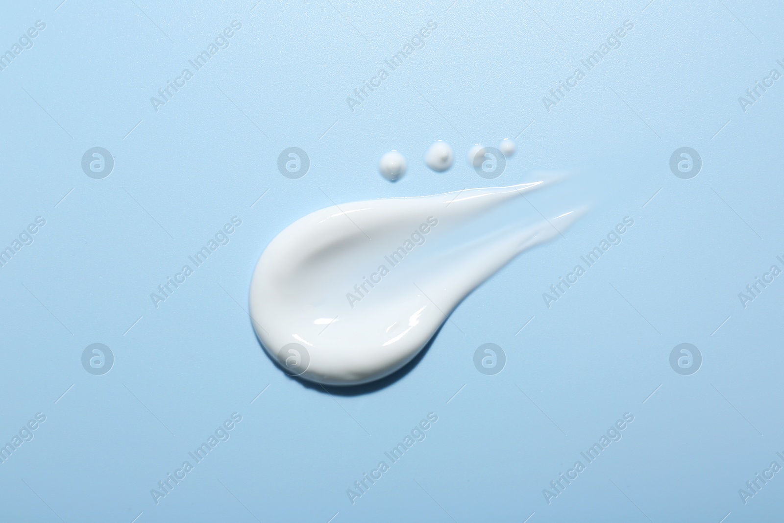 Photo of Sample of face cream on light blue background, top view