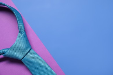 Turquoise necktie on color background, top view. Space for text