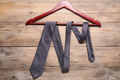 Hanger with black necktie on wooden table, top view