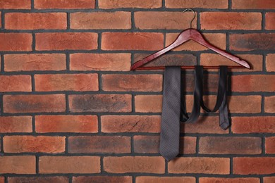 Photo of Hanger with black necktie on red brick wall. Space for text
