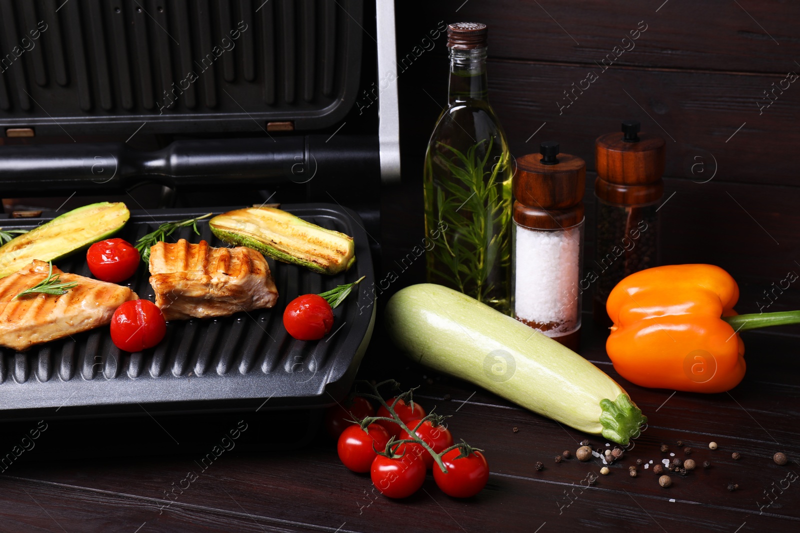 Photo of Electric grill with different products on wooden table