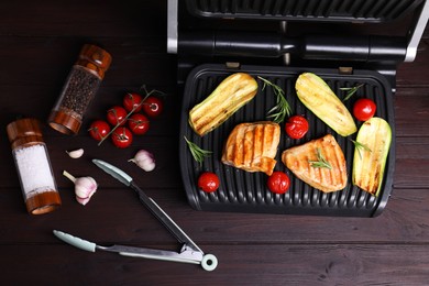 Flat lay composition with electric grill and different products on wooden table