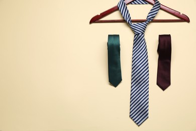 Photo of Hanger and neckties on beige background, flat lay. Space for text