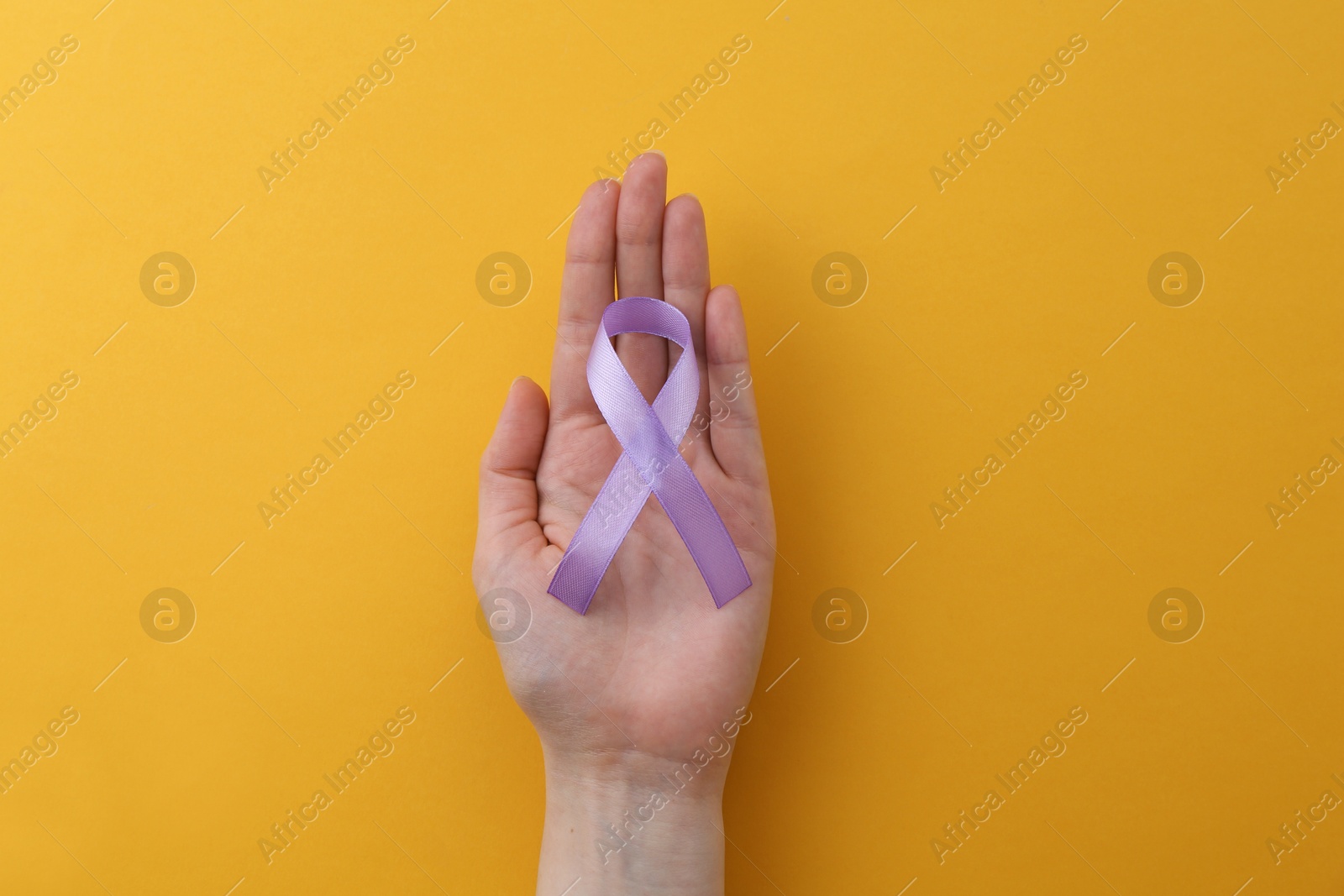 Photo of Woman with violet awareness ribbon on orange background, top view