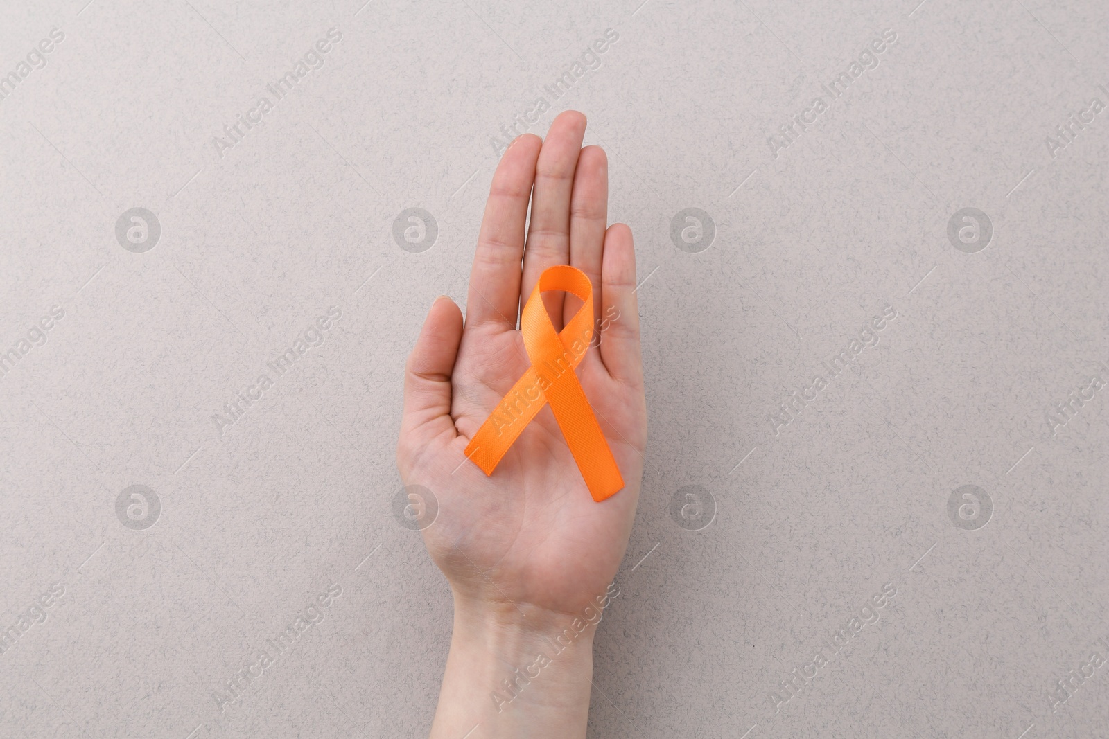 Photo of Woman with orange awareness ribbon on gray background, top view