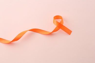Orange awareness ribbon on beige background, top view