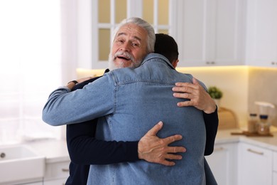 Photo of Happy dad and his son hugging at home