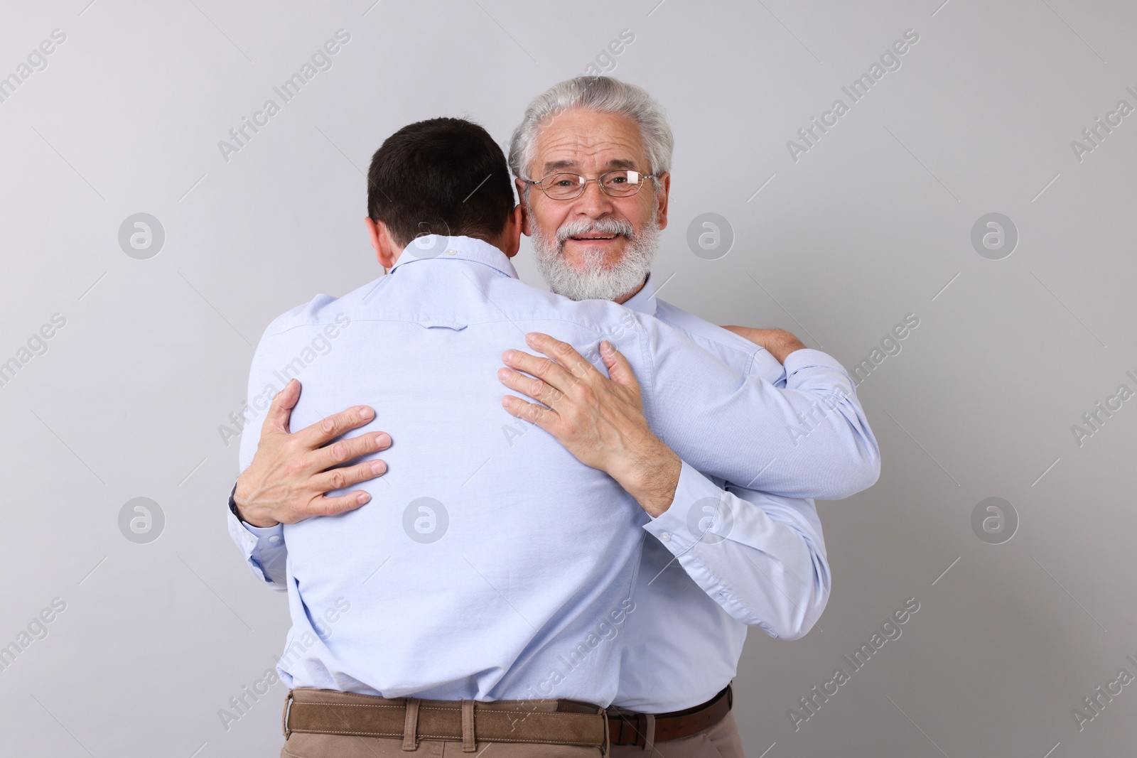 Photo of Happy dad and his son hugging on gray background