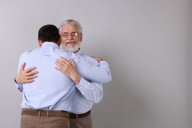 Happy dad and his son hugging on gray background, space for text