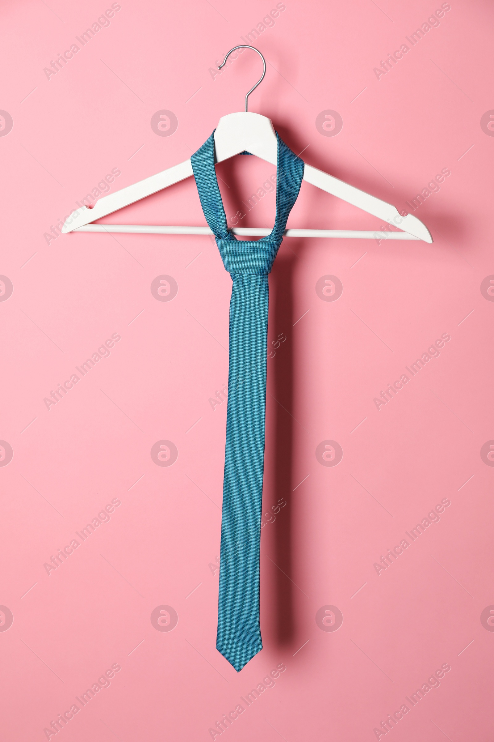 Photo of Hanger with turquoise tie on pink background
