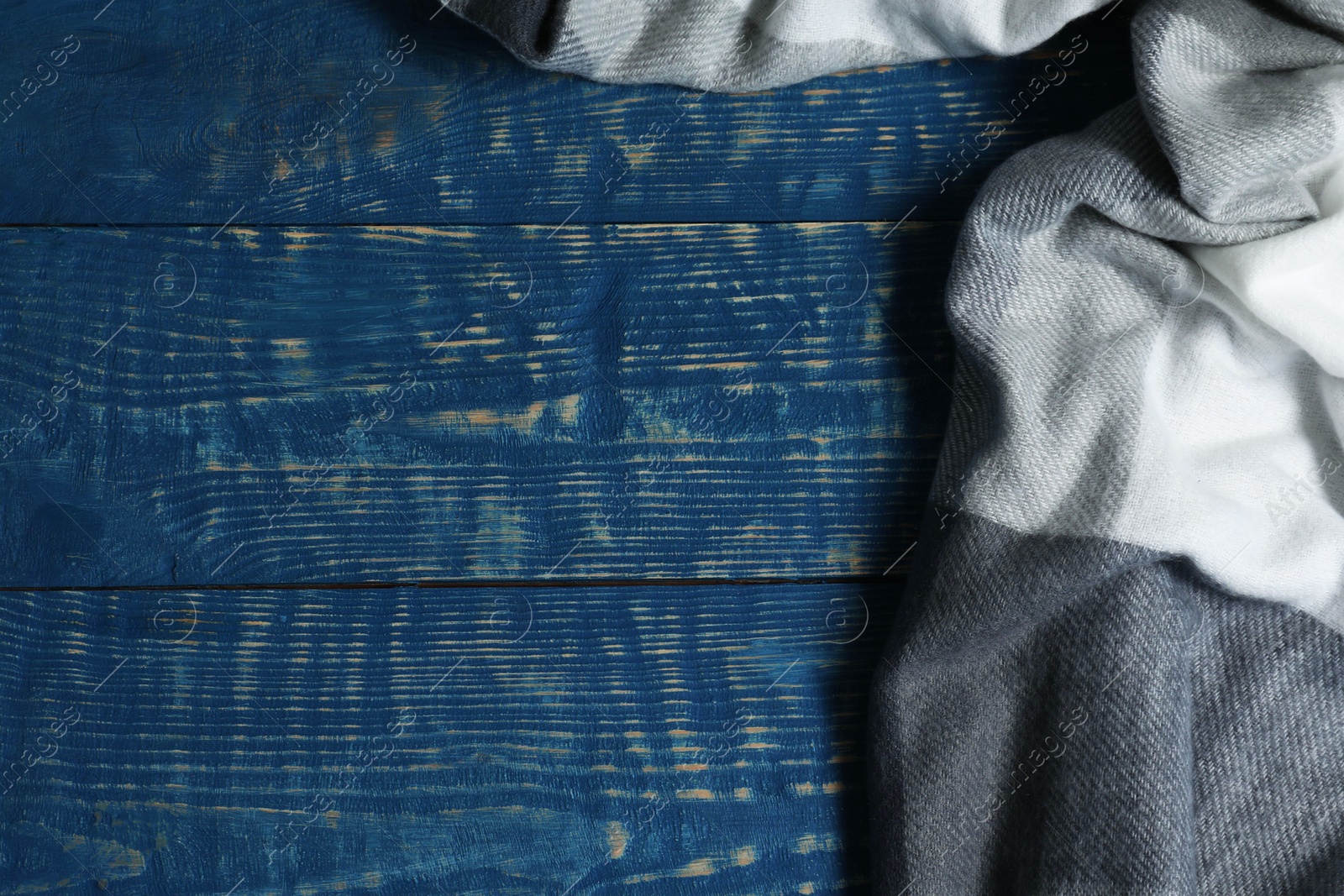 Photo of Soft scarf on blue wooden table, top view. Space for text