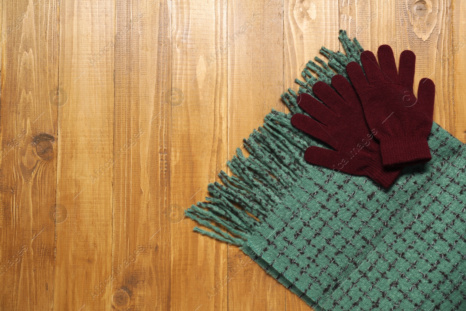 Photo of Soft green scarf and gloves on wooden table, top view. Space for text