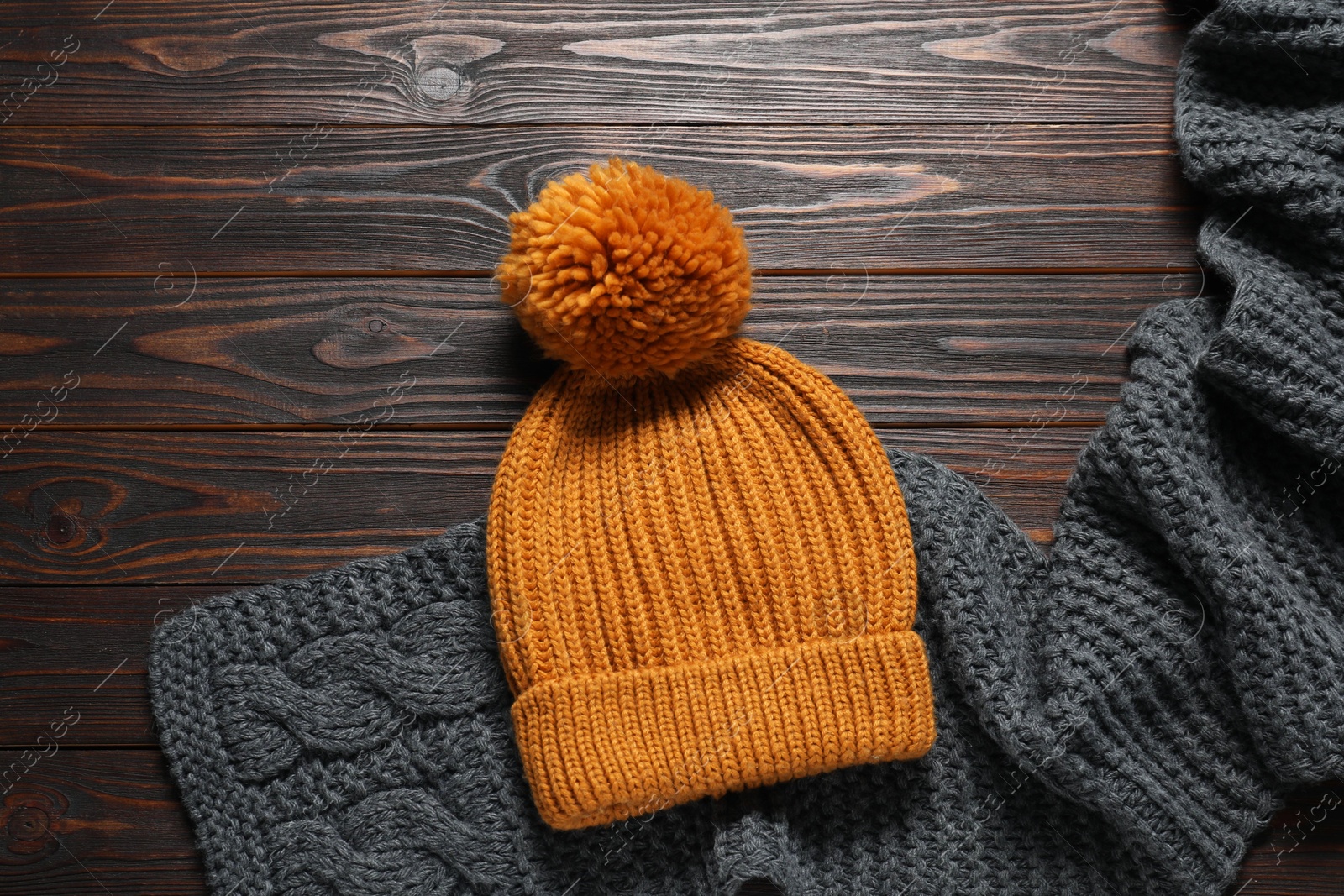 Photo of Knitted scarf and hat on wooden table, top view. Space for text