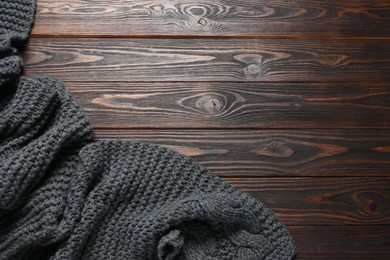 Gray knitted scarf on wooden table, top view. Space for text