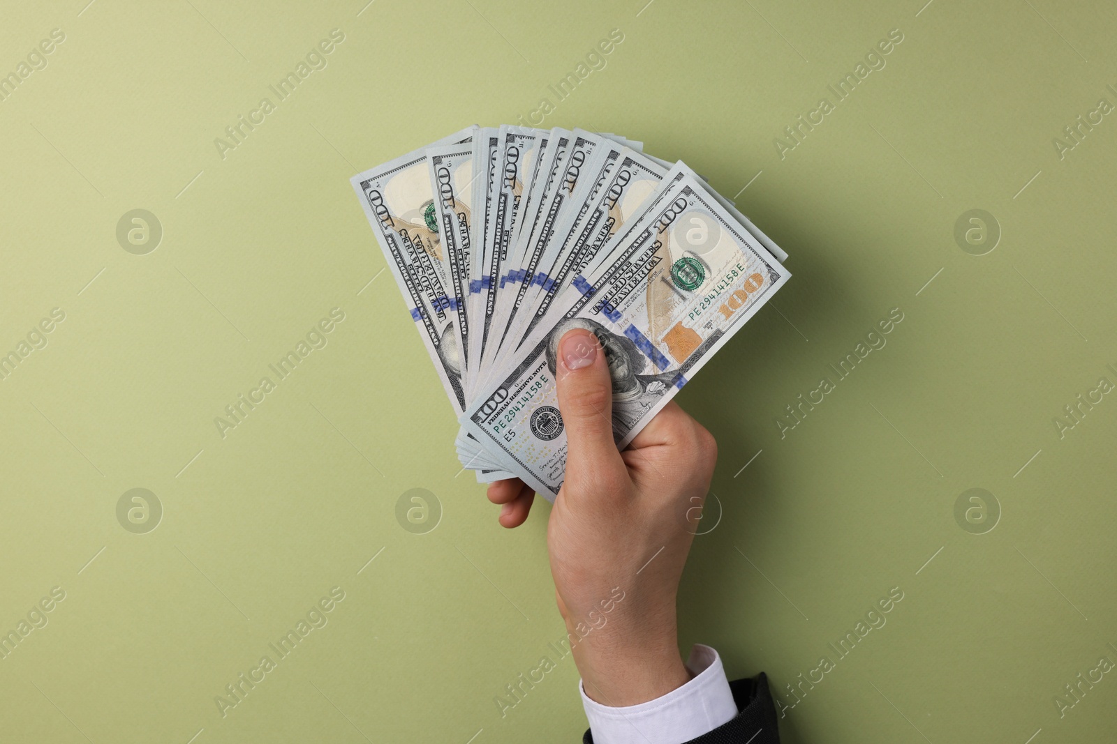 Photo of Money exchange. Man holding dollar banknotes on olive background, top view