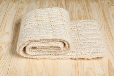 One knitted scarf on wooden table, closeup