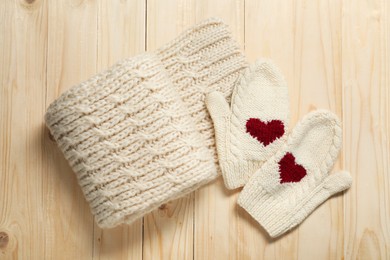 Knitted scarf and mittens on wooden table, flat lay