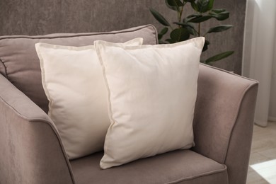 Photo of Soft pillows on grey armchair in room