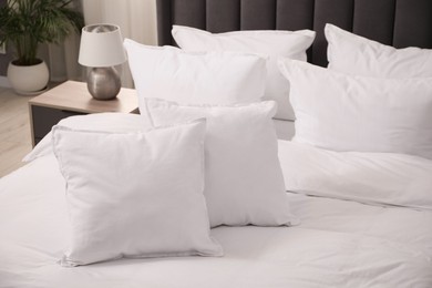 Photo of Many soft white pillows and duvet on bed indoors