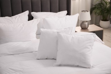 Photo of Many soft white pillows and duvet on bed indoors