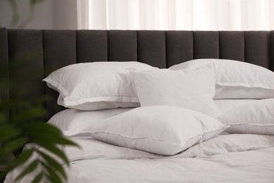 Photo of Many soft white pillows and duvet on bed indoors