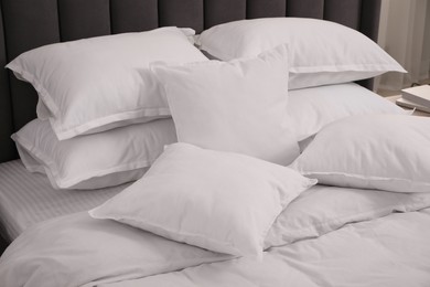 Photo of Many soft white pillows and duvet on bed indoors