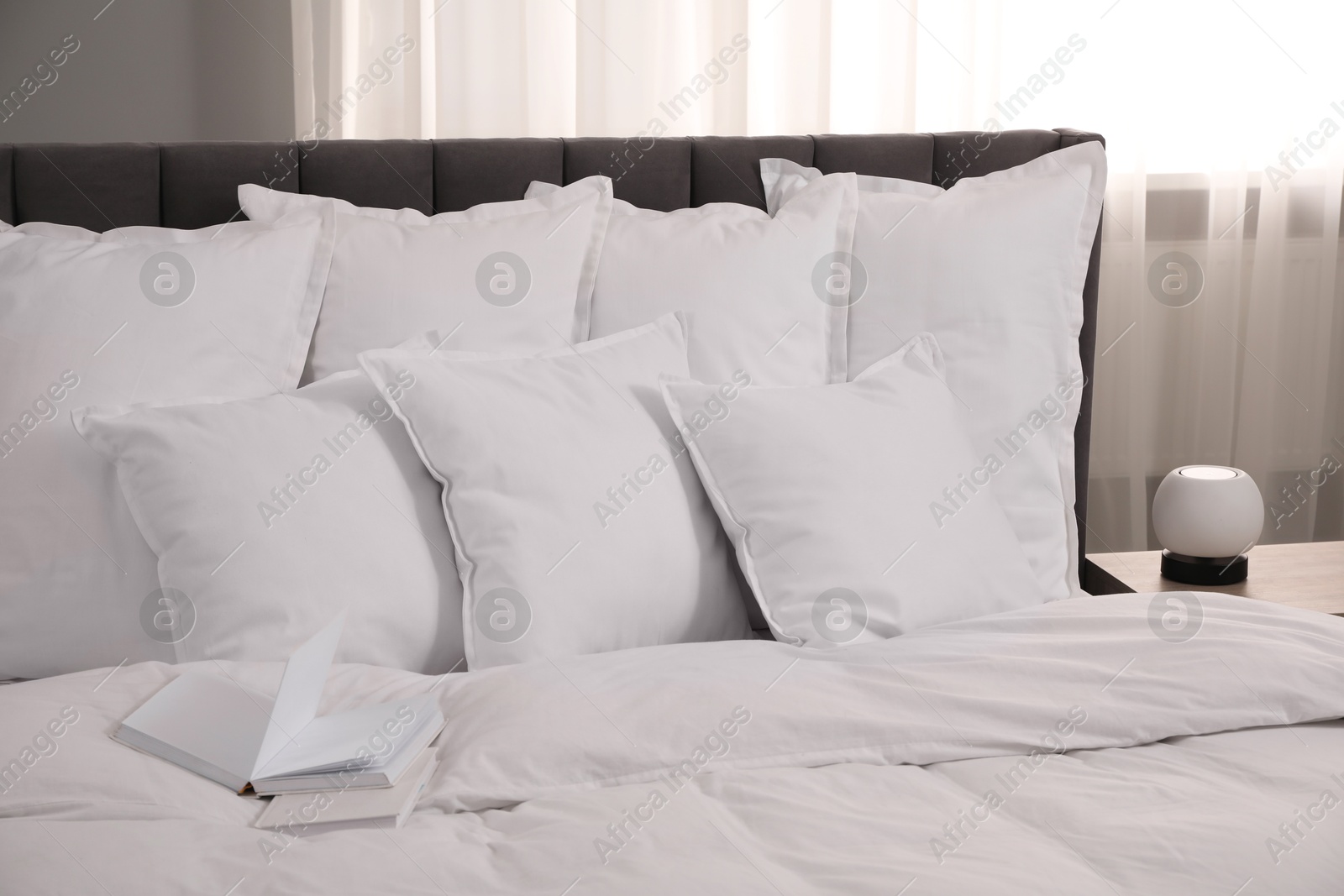 Photo of Many soft white pillows and duvet on bed indoors