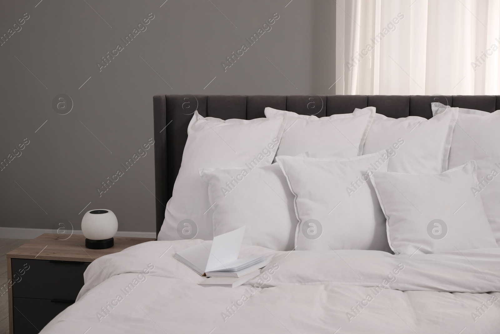 Photo of Many soft white pillows and duvet on bed indoors