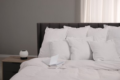 Many soft white pillows and duvet on bed indoors