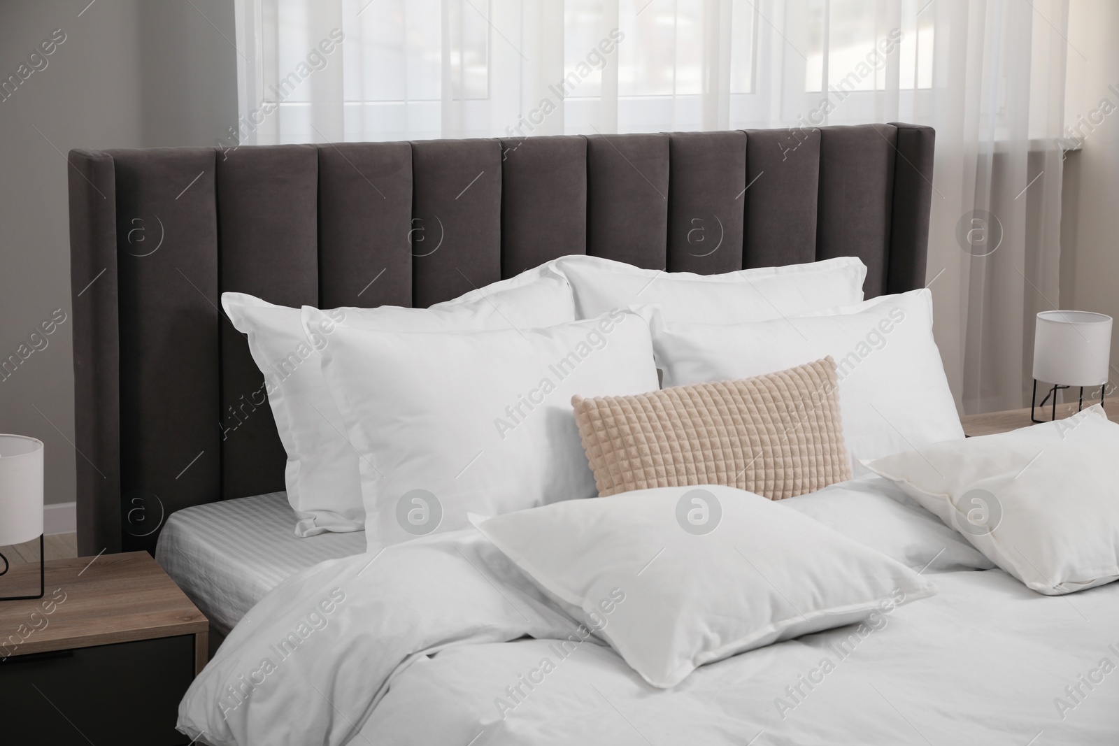 Photo of Many soft white pillows and duvet on bed indoors