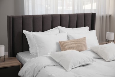 Photo of Many soft white pillows and duvet on bed indoors