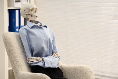 Waiting concept. Human skeleton sitting in armchair at office, space for text