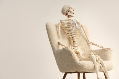 Waiting concept. Human skeleton sitting in armchair indoors, space for text