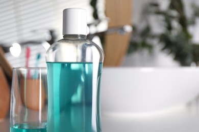 Photo of Bottle and glass of mouthwash in bathroom, closeup