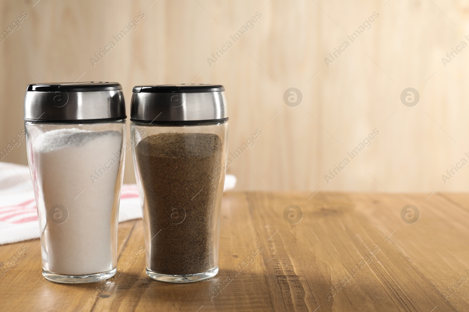 Photo of Salt and pepper shakers on wooden table, closeup. Space for text