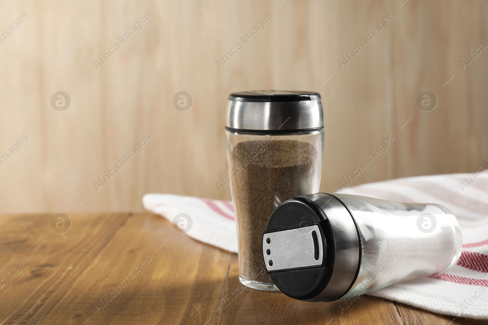 Photo of Salt and pepper shakers on wooden table, closeup. Space for text